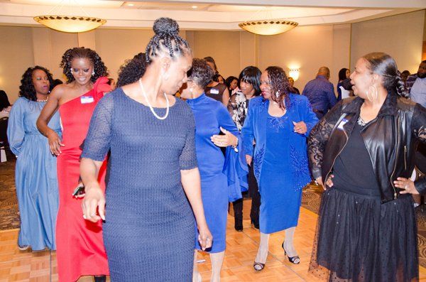 Group of people dancing in a ballroom, wearing colorful dresses.