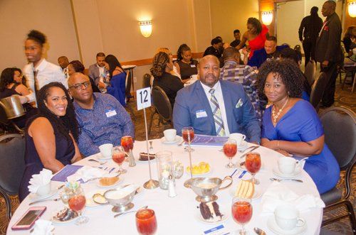 People at a formal event seated at a round table with drinks.