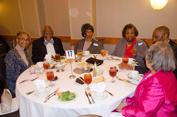 People seated around a round table at an event, with food and drinks.