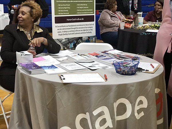 Woman at a table with brochures and a sign that reads 