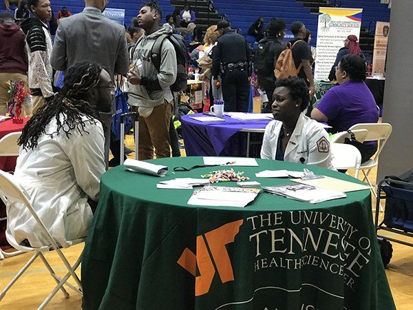 People at a career fair, many tables with information, a green University of Tennessee table is visible.