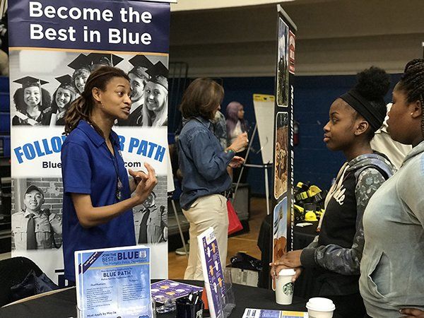 People at a booth, discussing education. 