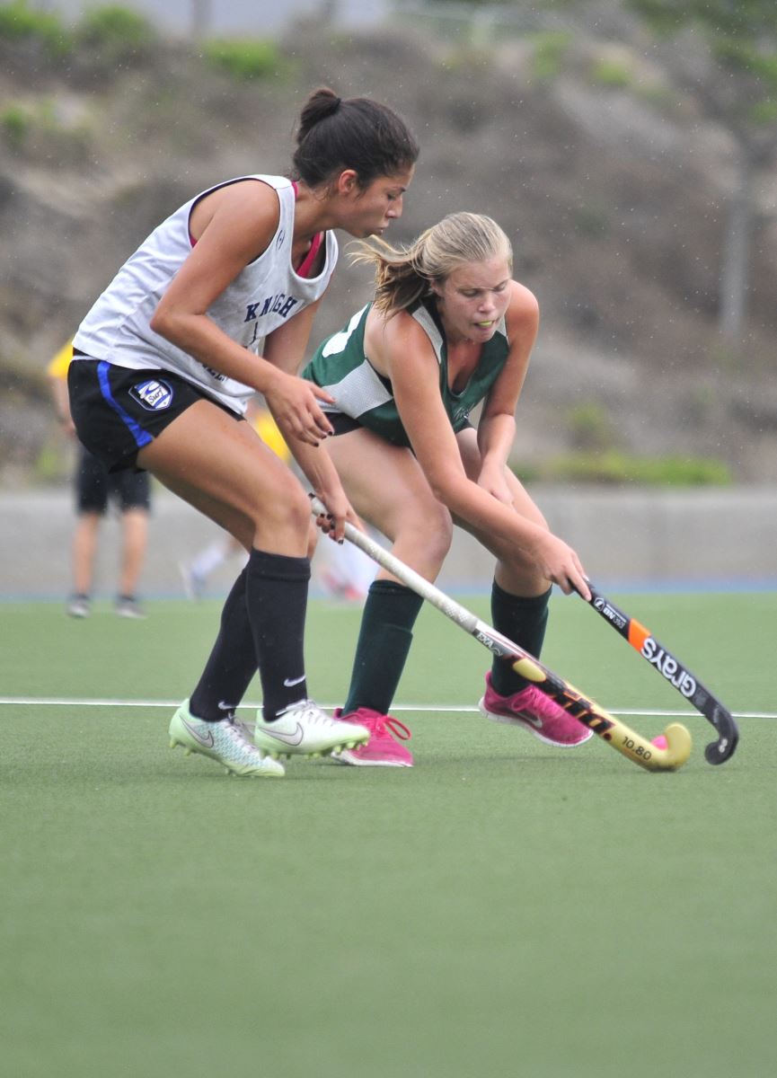 girls playing field hockey