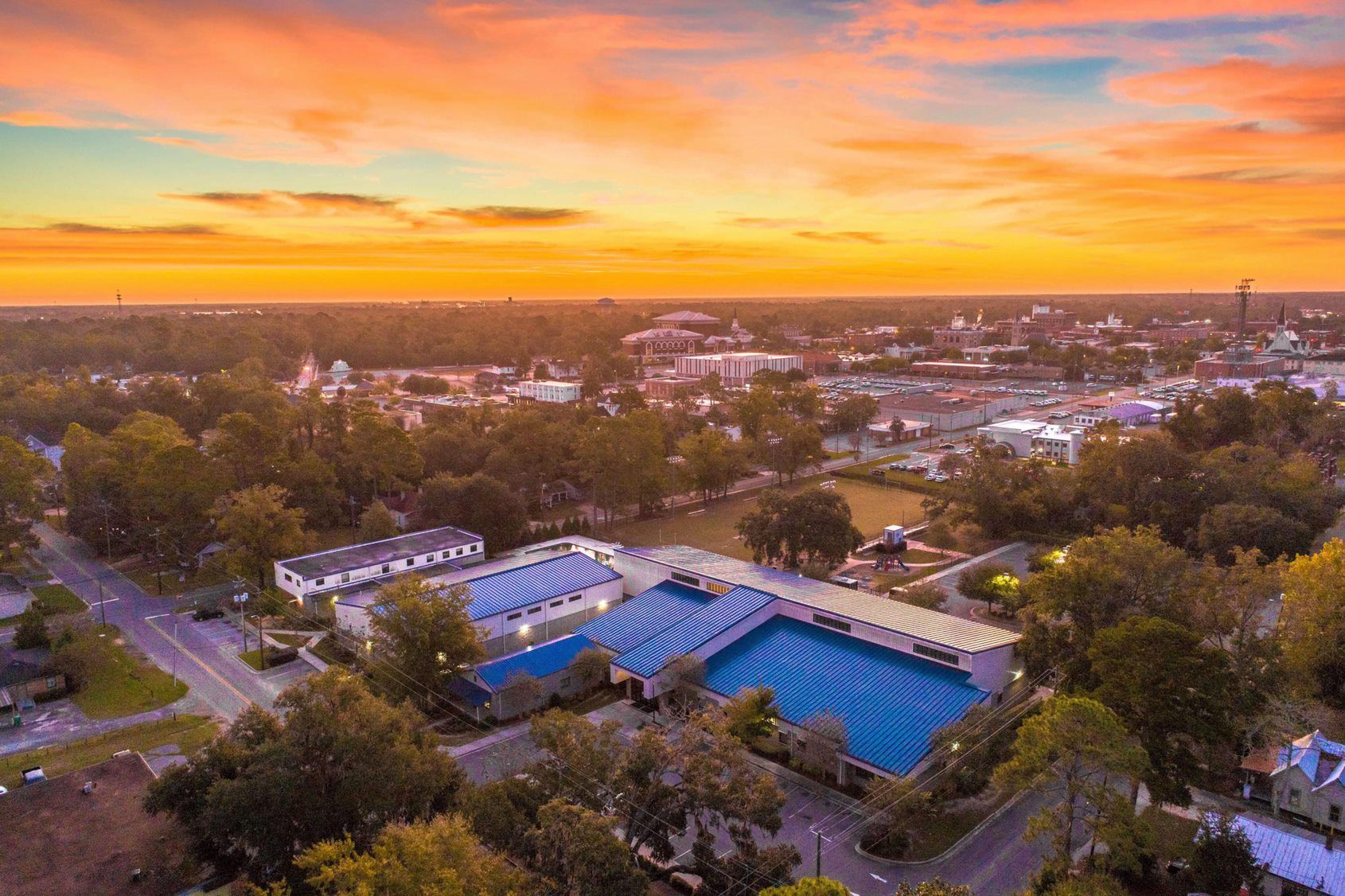 Aerial view of the Boys & Girls Club of Valdosta location, trees, and buildings under a vibrant sunset.