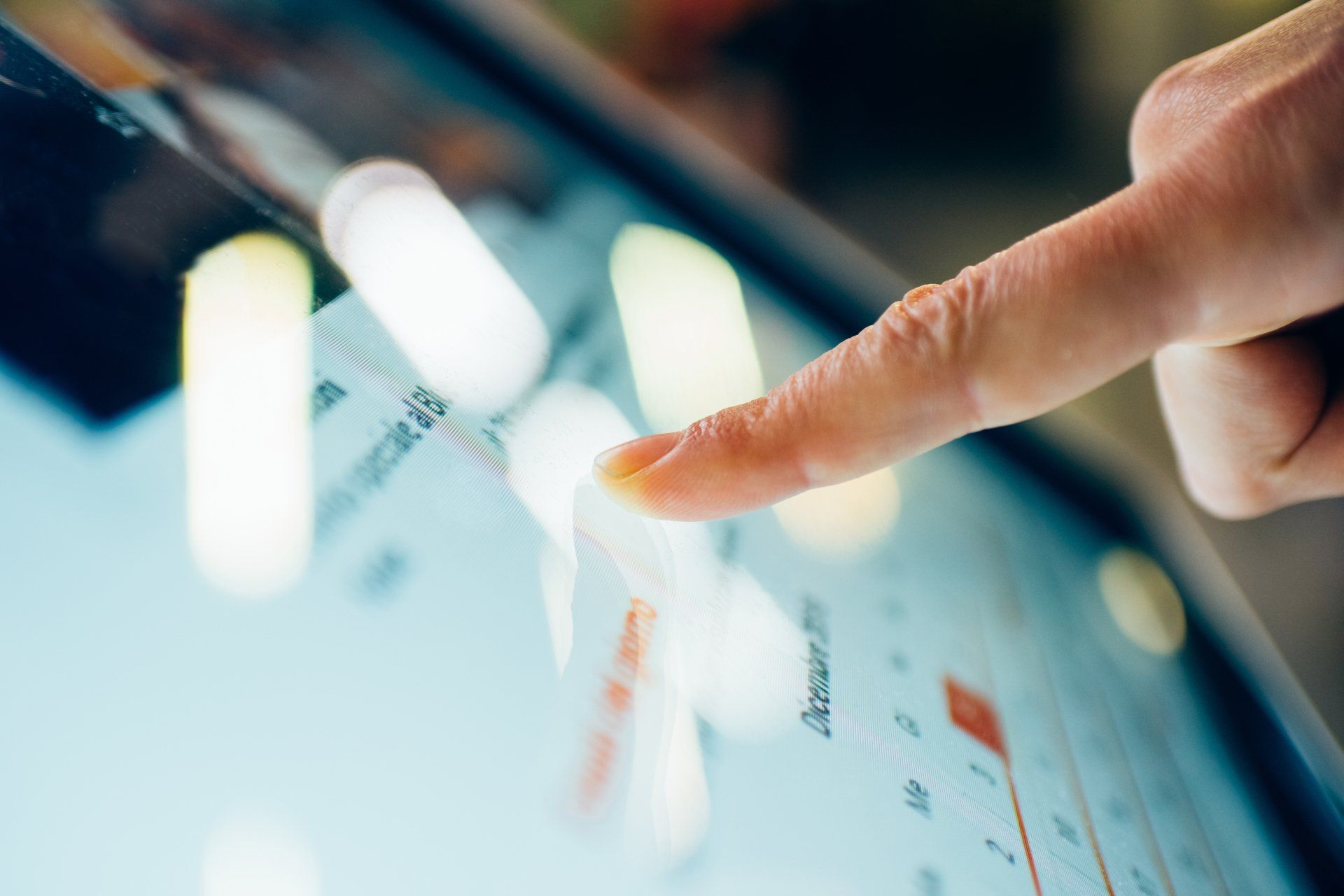 Finger tapping a tablet screen with charts and bright interface