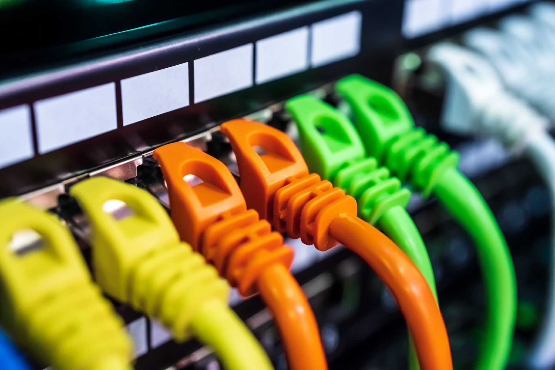 Colorful Ethernet cables plugged into a network switch, with yellow, orange, and green connectors.