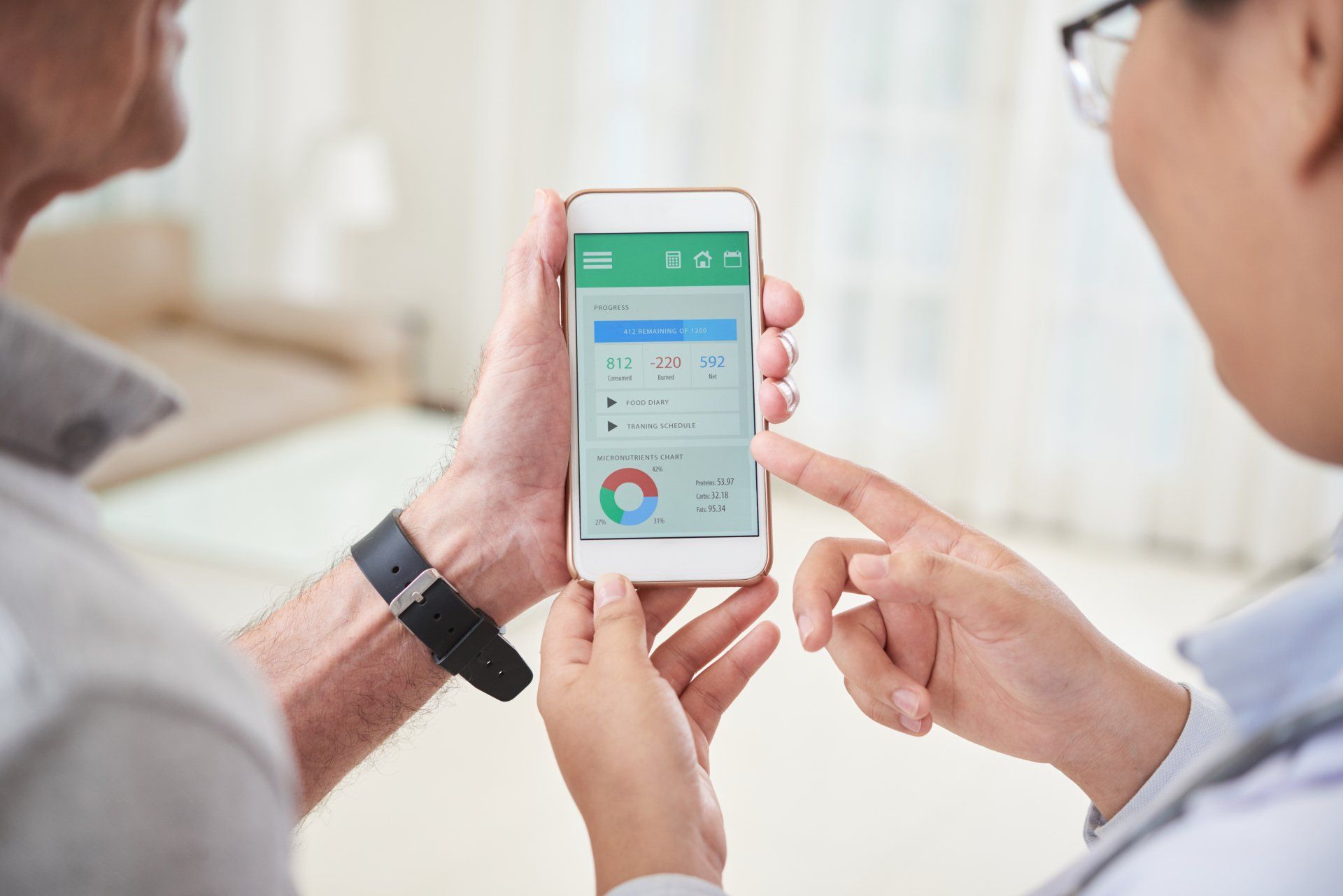 Two people reviewing health stats on a smartphone in a bright office