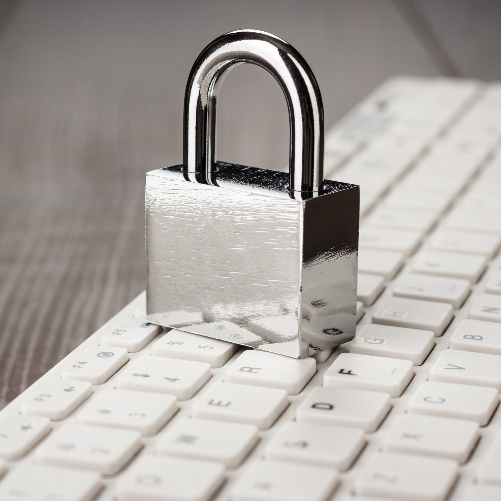 Silver padlock on a white keyboard, symbolizing security or locked access
