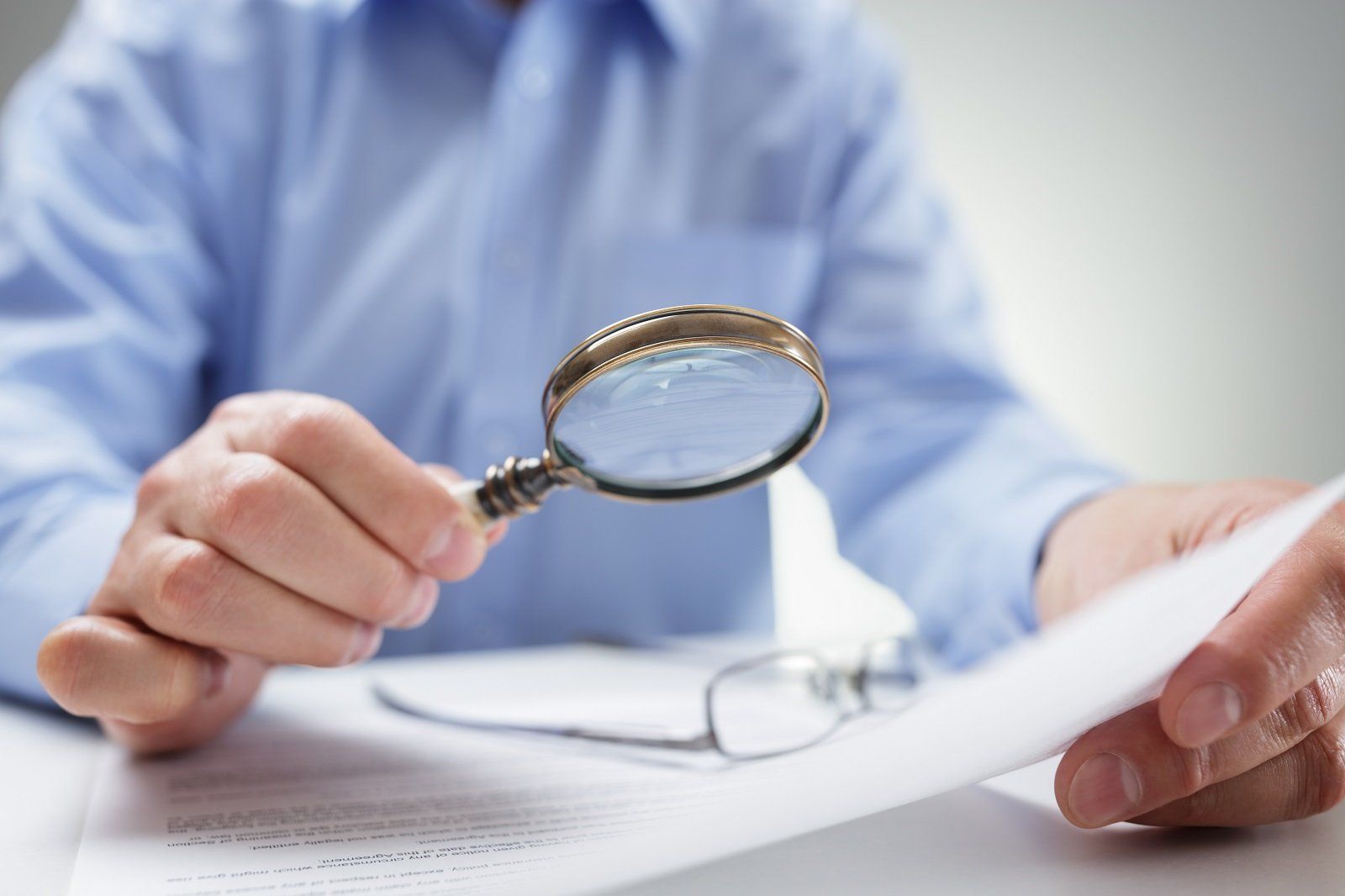uomo che legge un documento con lente d'ingrandimento