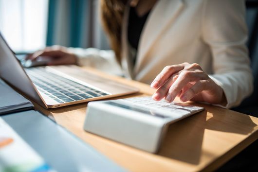 Woman doing calculation while working on laptop
