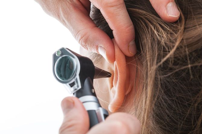 Closeup of examining ear with an Otoscope