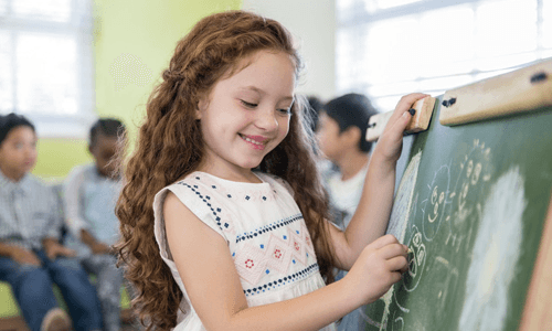 A girl writing on green board