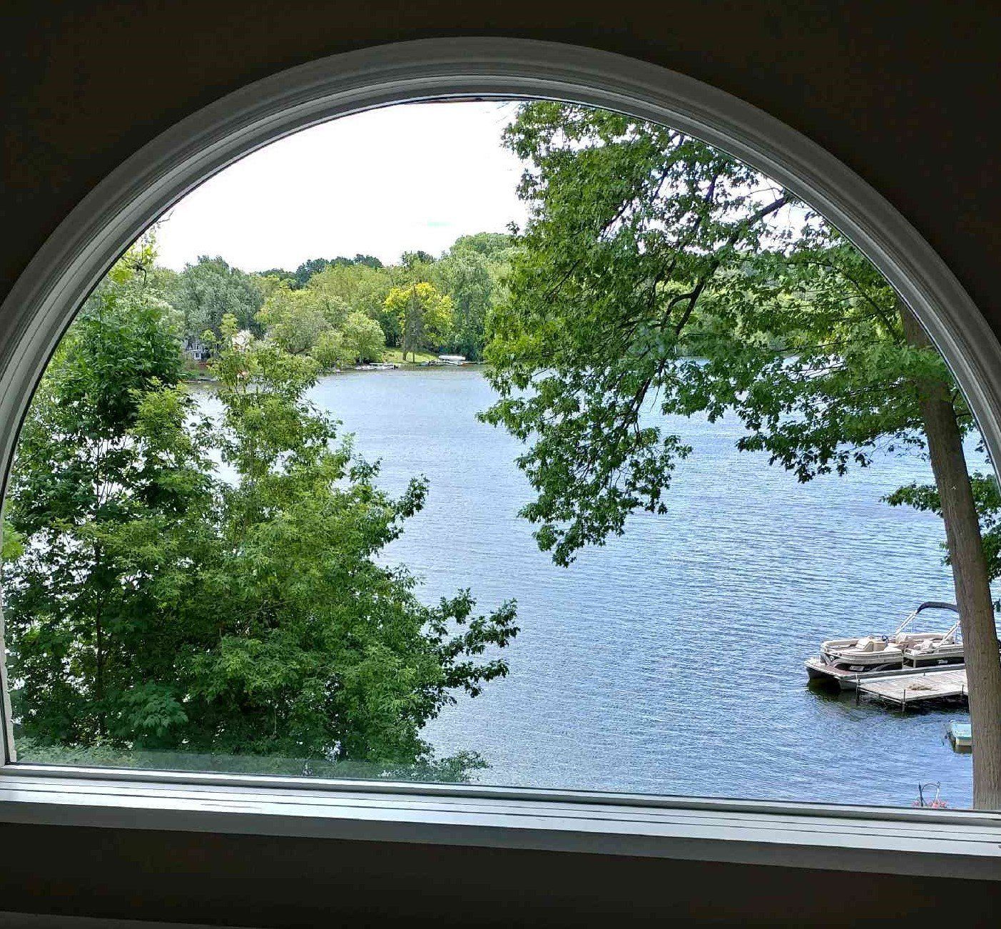 A view of a lake through an arched window. Devine Shine Window Cleaning Canton MI.