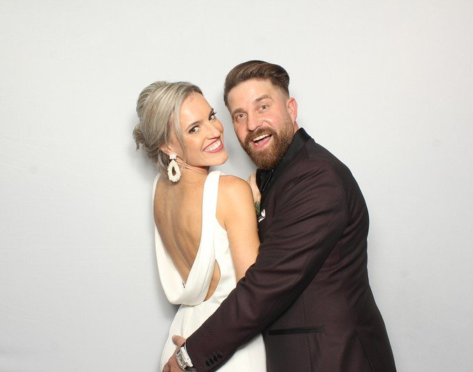 A bride and groom posing for a photo in a glam Photo Booth at their wedding.