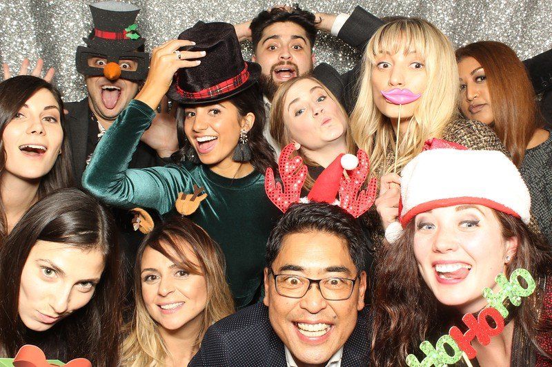 Group of people smiling and posing with props in a photo booth.