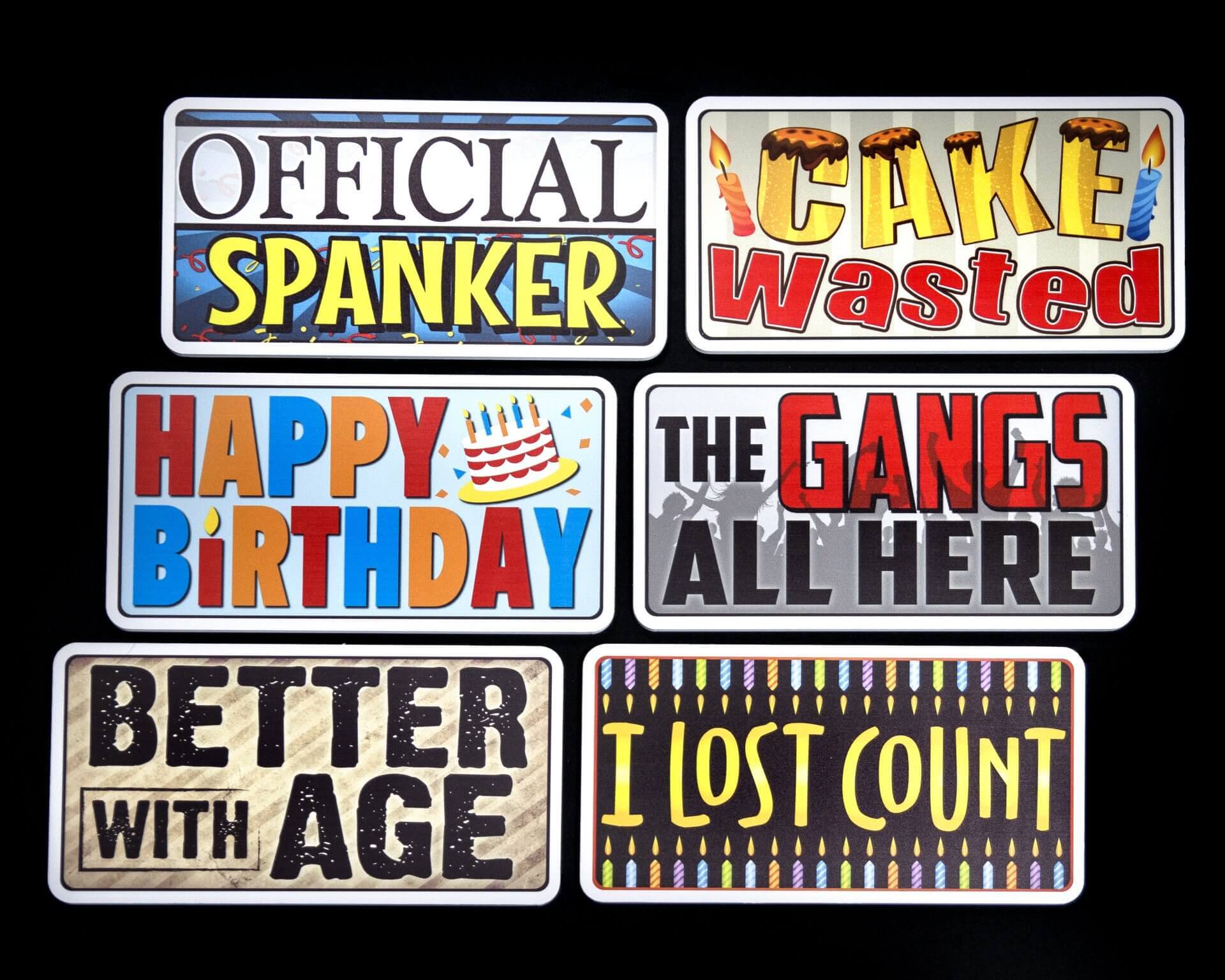 Six humorous birthday signs with text on a black background.