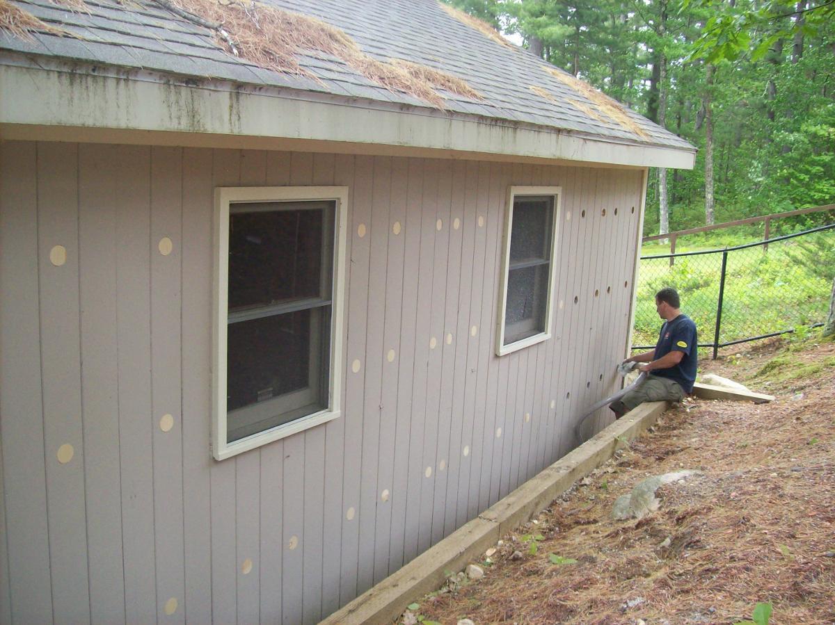 Insulation contractor working on exterior of Scarborough, ME cabin