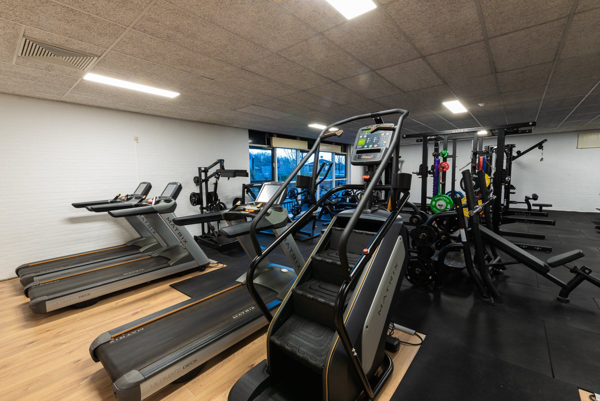 Een fitnessruimte met loopbanden, trappen en andere fitnessapparatuur.
