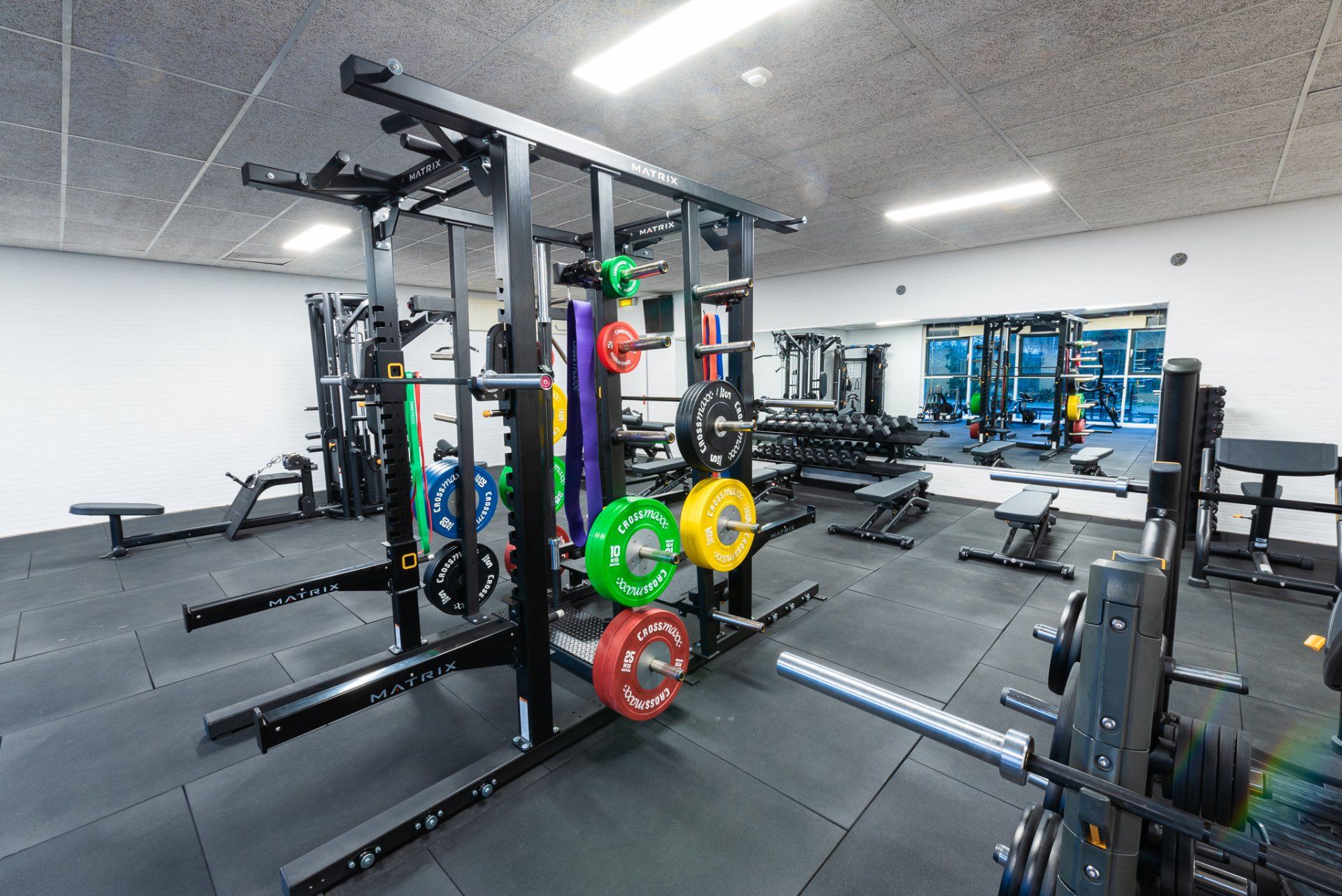 Een sportschool vol met veel fitnessapparatuur en een grote spiegel.