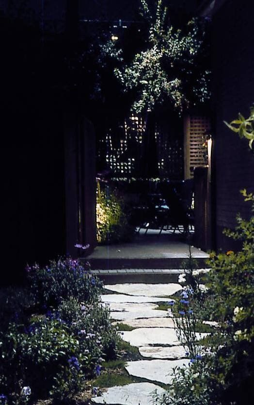 A stone walkway leading to a house at night