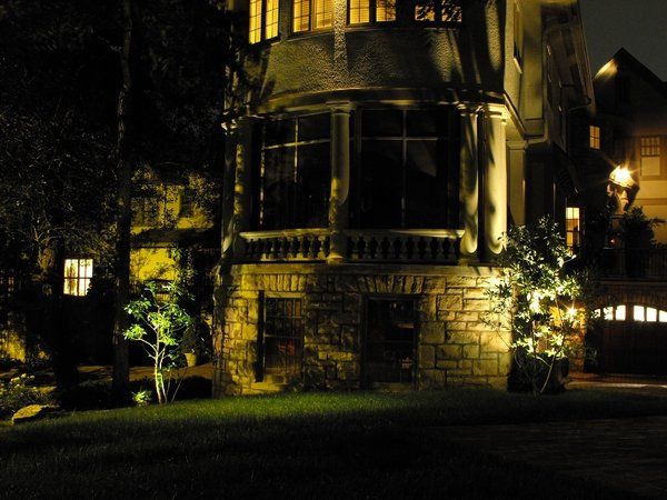 A large house is lit up at night with trees in front of it