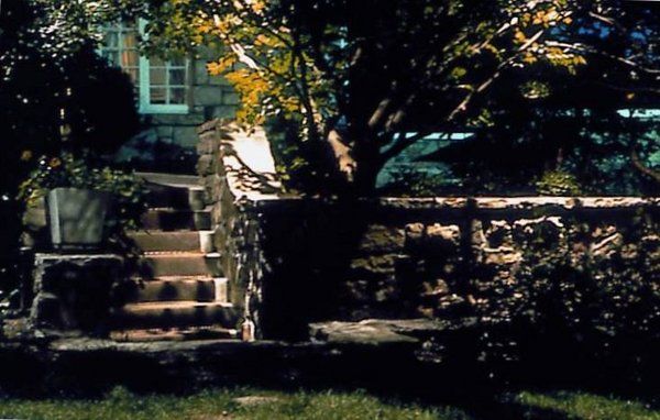 A stone wall with stairs leading up to a house