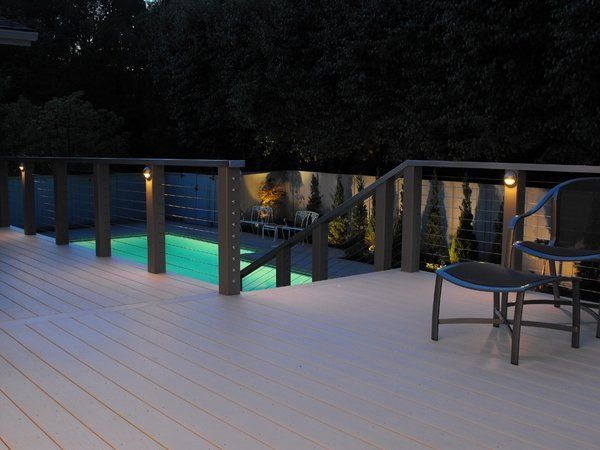 A deck with a chair and ottoman next to a swimming pool