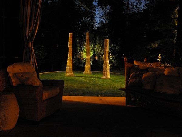 A patio with a couch , chairs , and a gazebo at night.