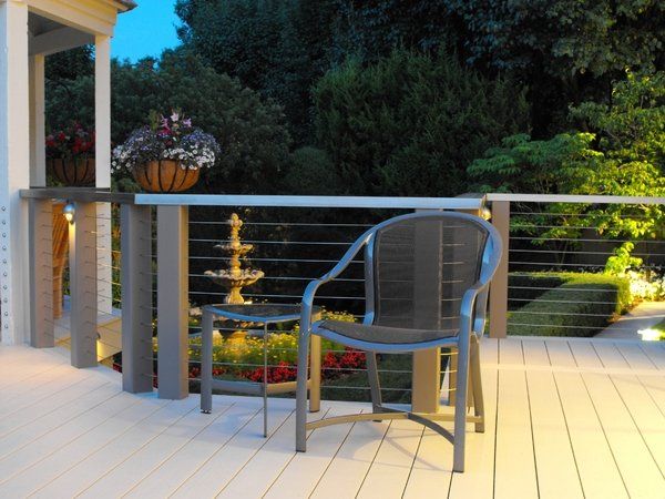 A deck with a chair and a table with a fountain in the background