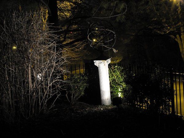 A statue is lit up at night in a dark forest.