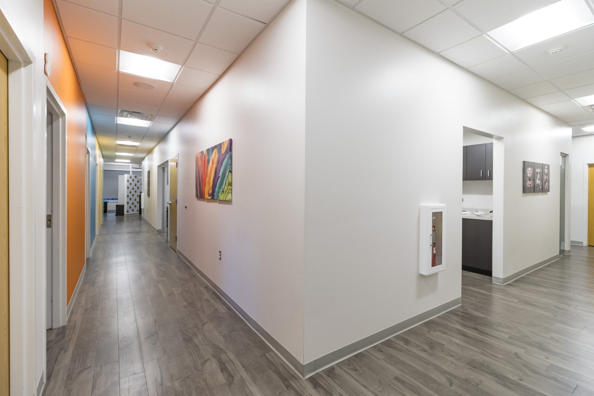 Long hallway with white walls, doors, and a fire extinguisher.