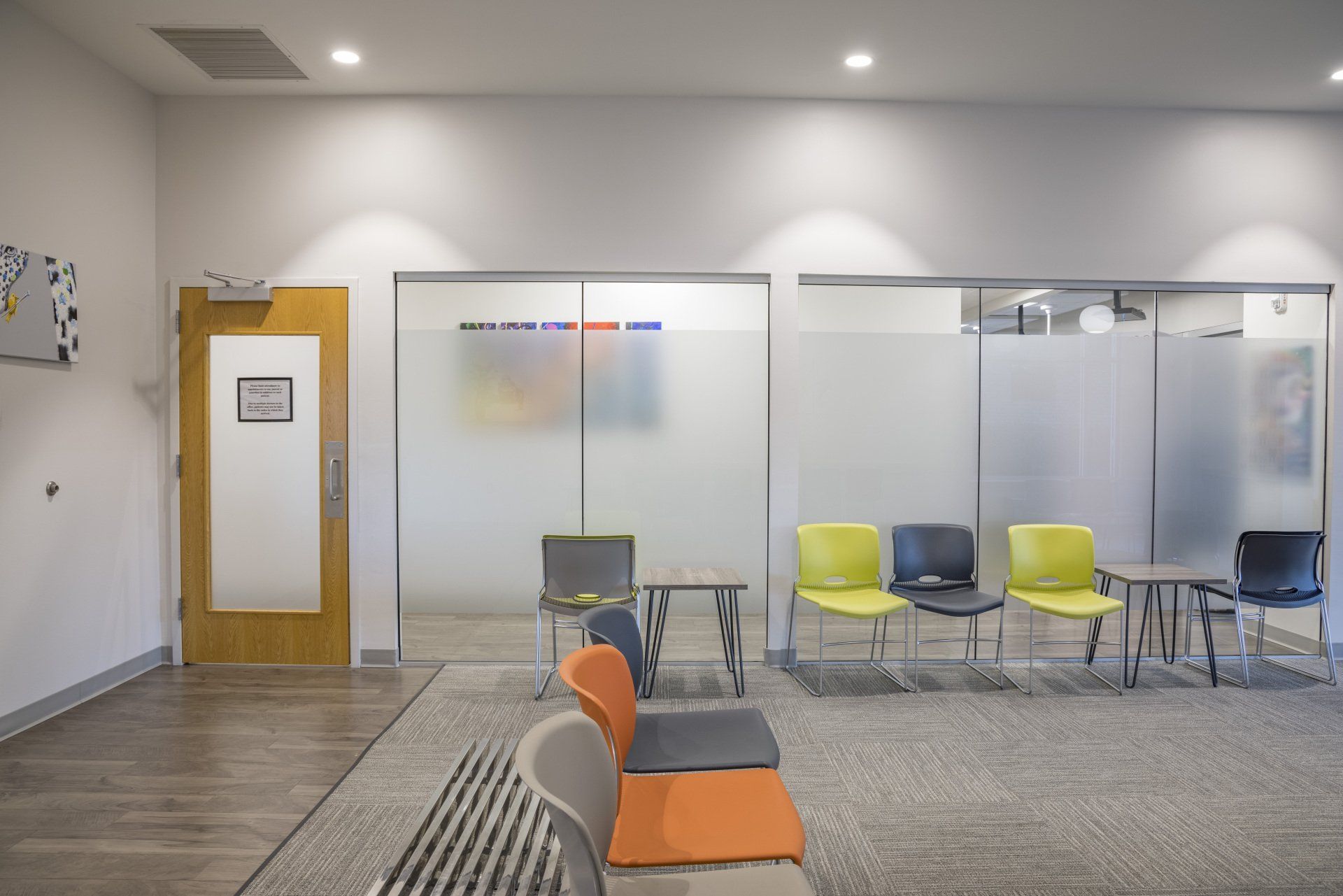 Waiting room with chairs, frosted glass, and a door.
