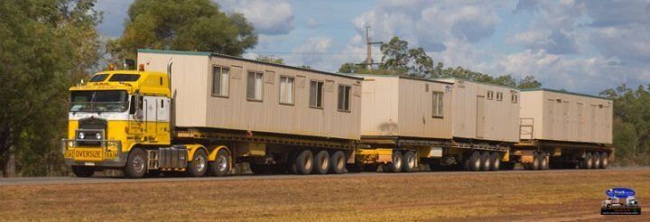 A yellow semi truck is carrying a train of containers- Slingshot Haulage in Katherine, NT