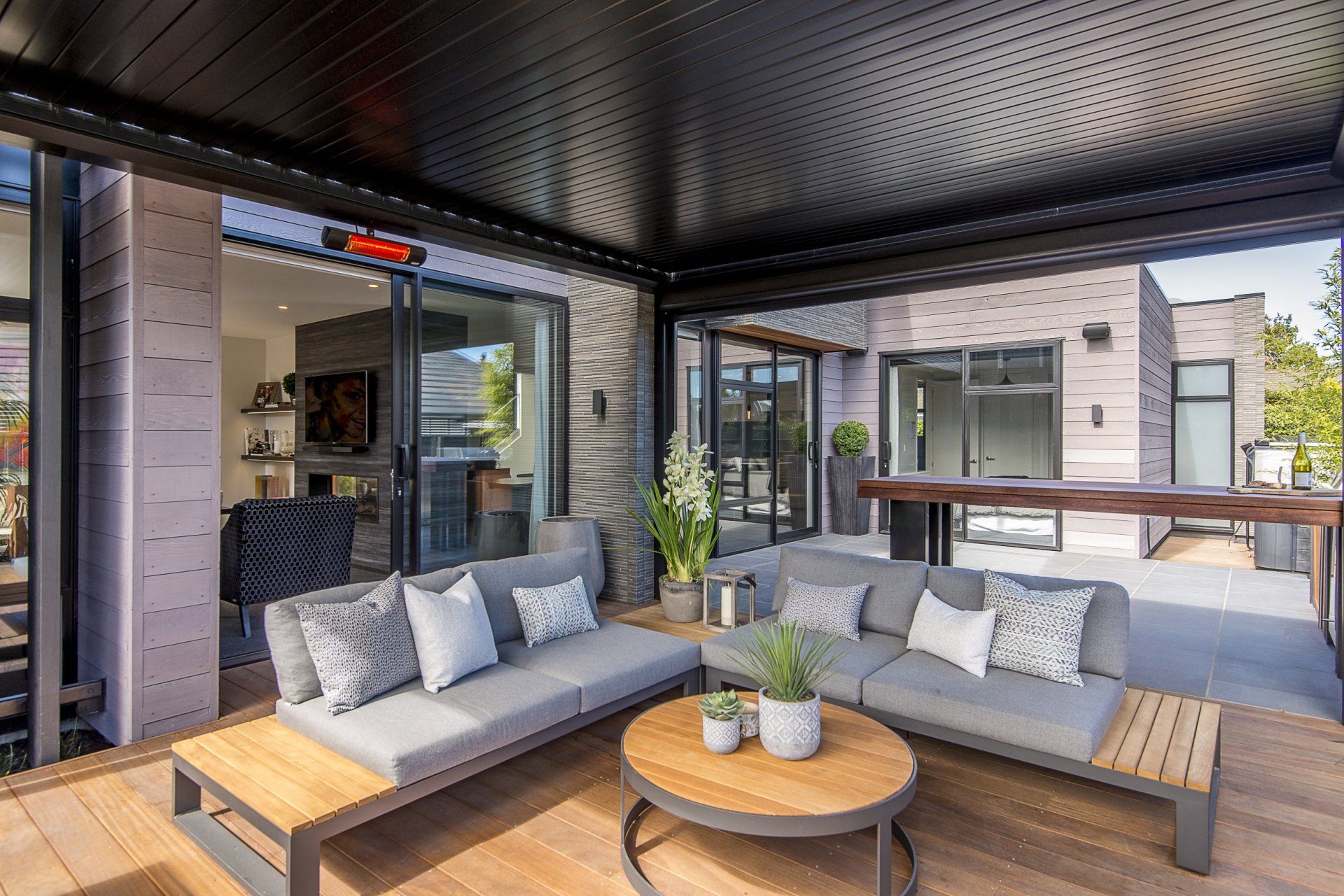A living room with a couch and a table under a pergola.