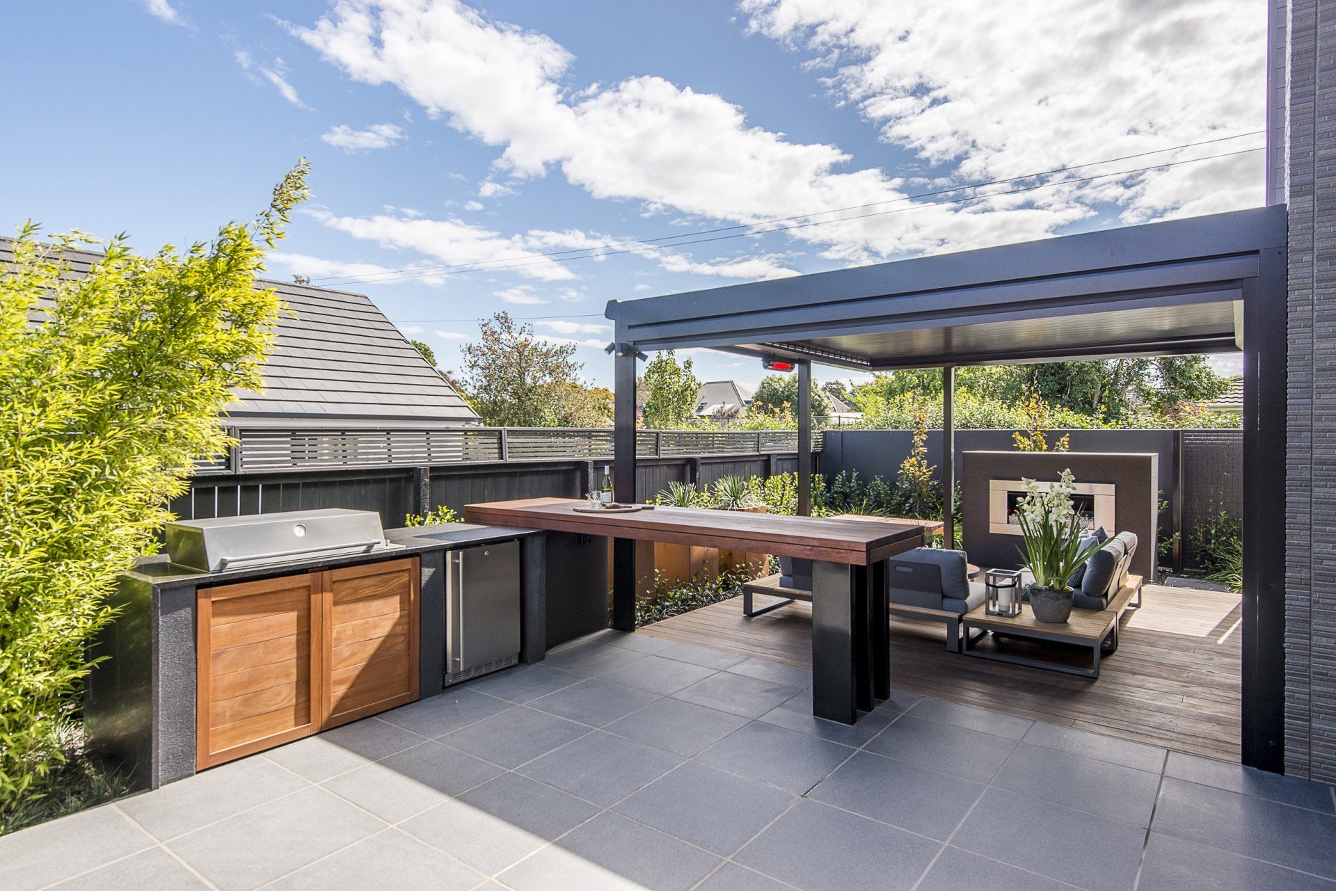A patio with a large wooden table and a grill.