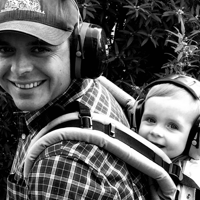 A man wearing headphones is carrying a baby in a backpack