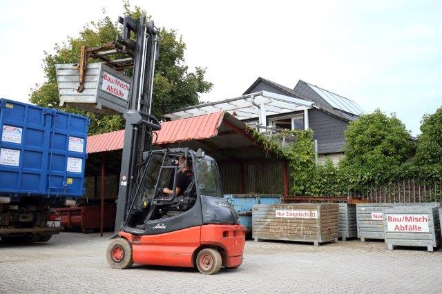 Roter Gabelstaplet transportiert Abfall Container