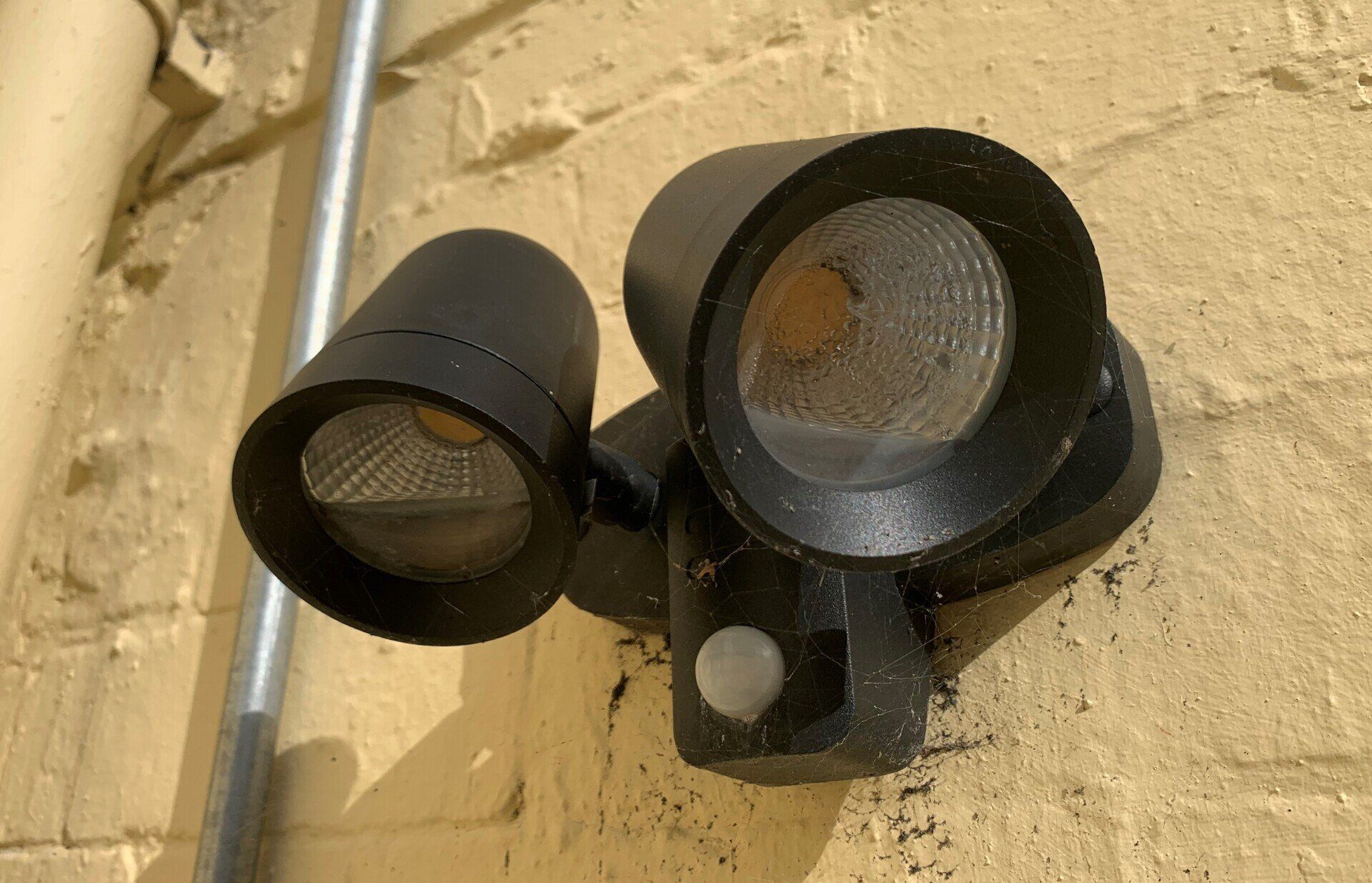 A black light with a motion sensor attached to a brick wall.