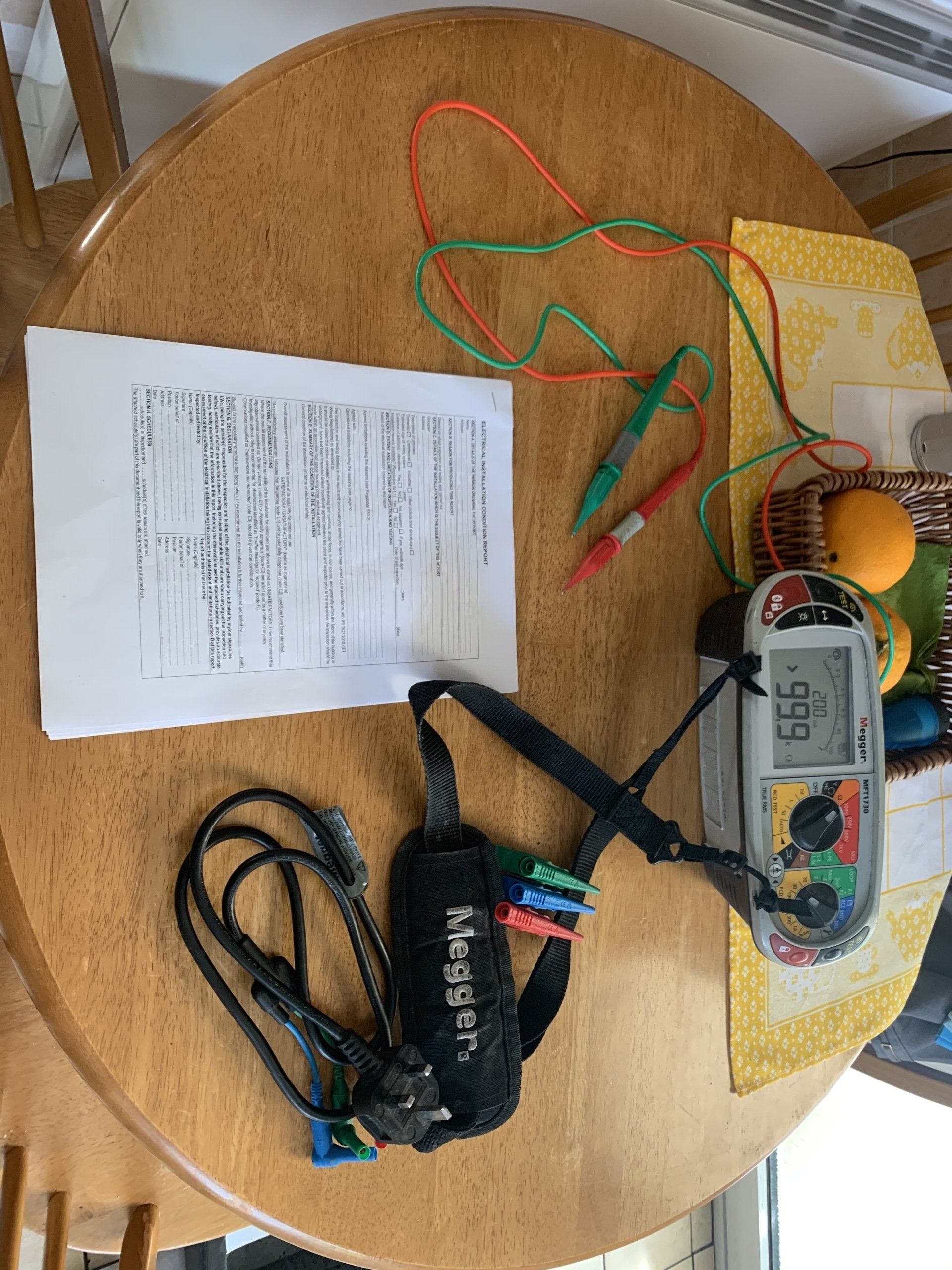 A wooden table with a bunch of wires and a thermometer on it.