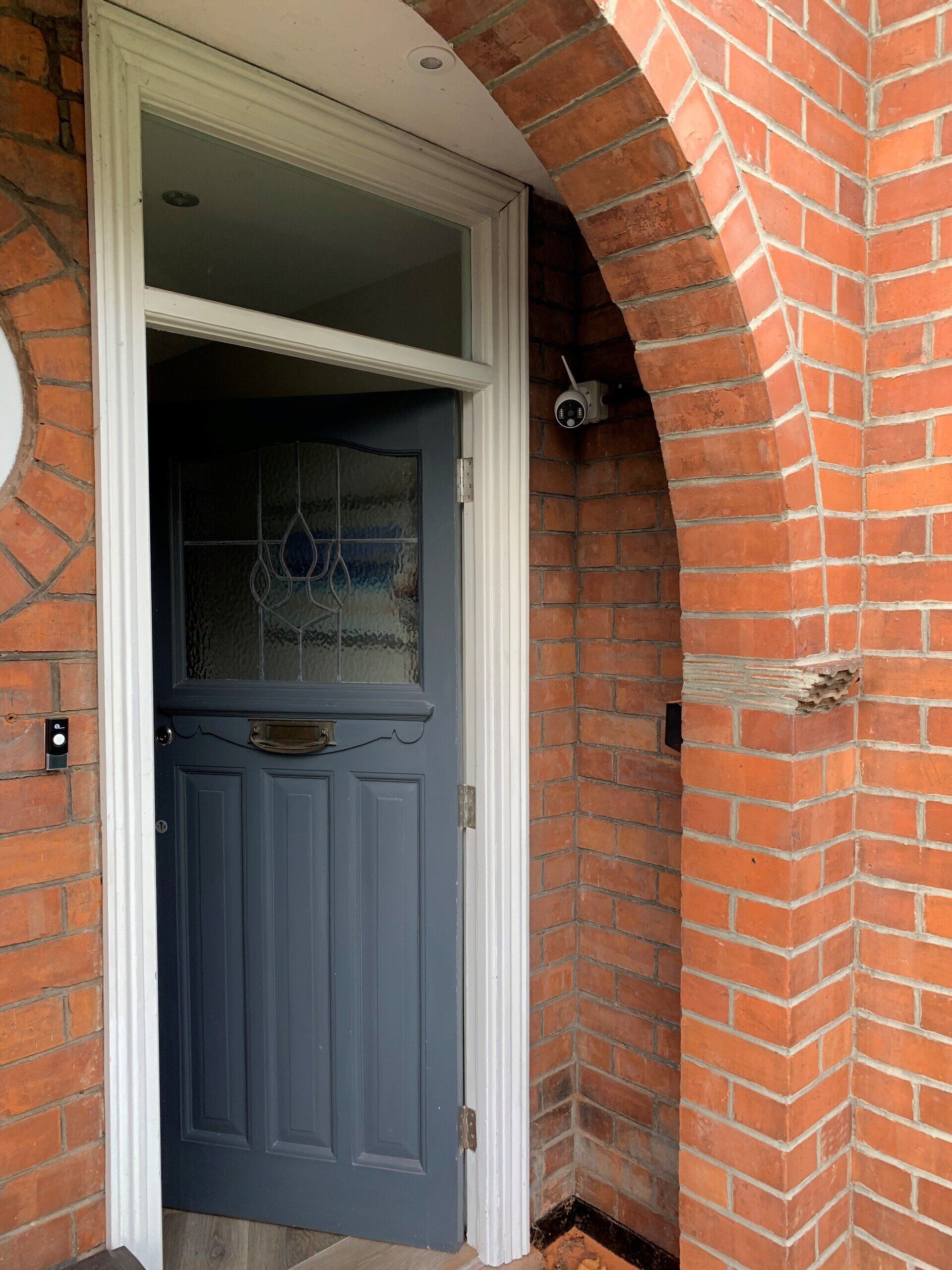 A blue door is open on a red brick building.