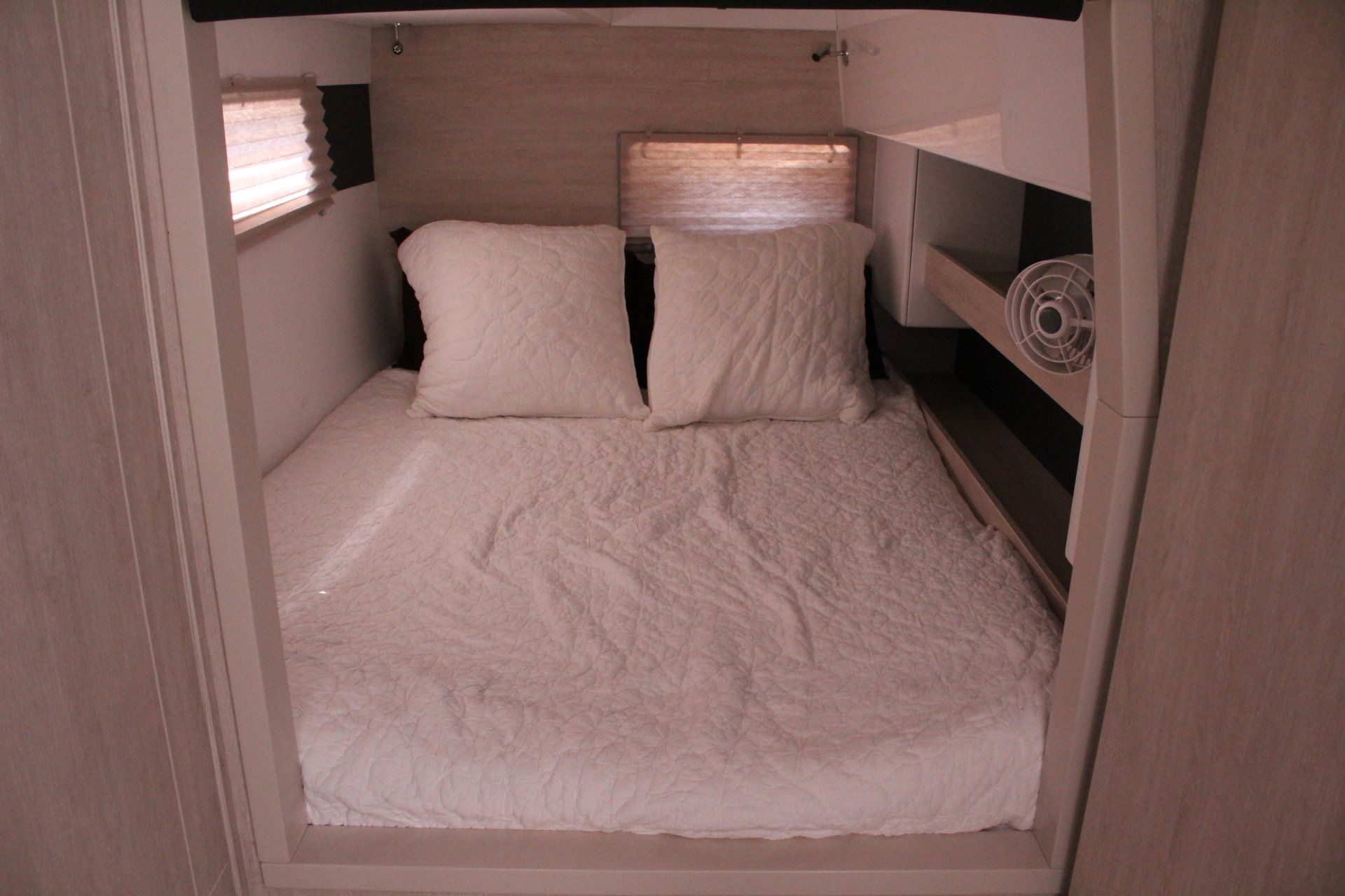A bed with white sheets and pillows in a room
