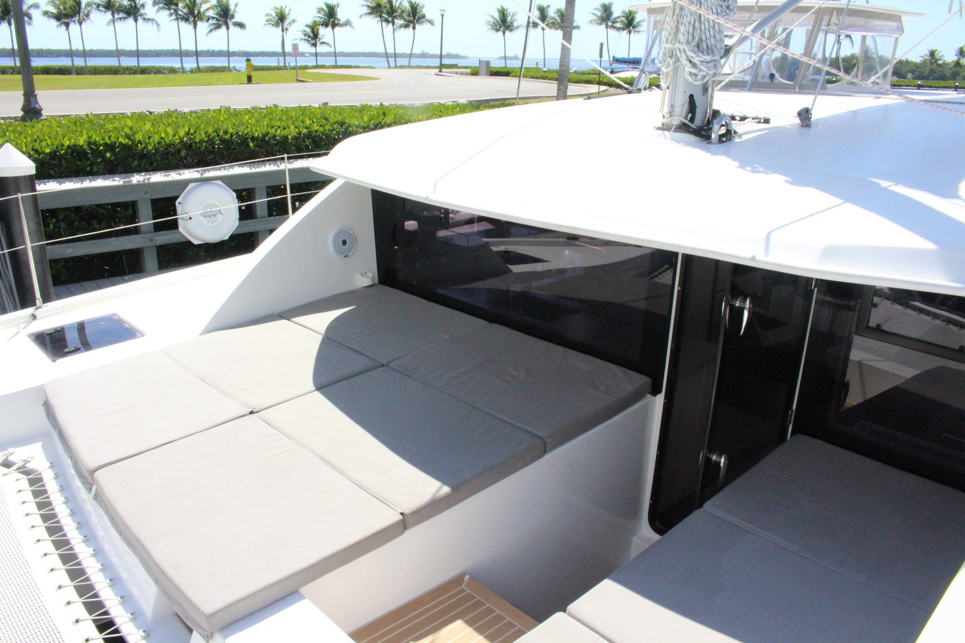 A white boat with a couch on the deck and palm trees in the background