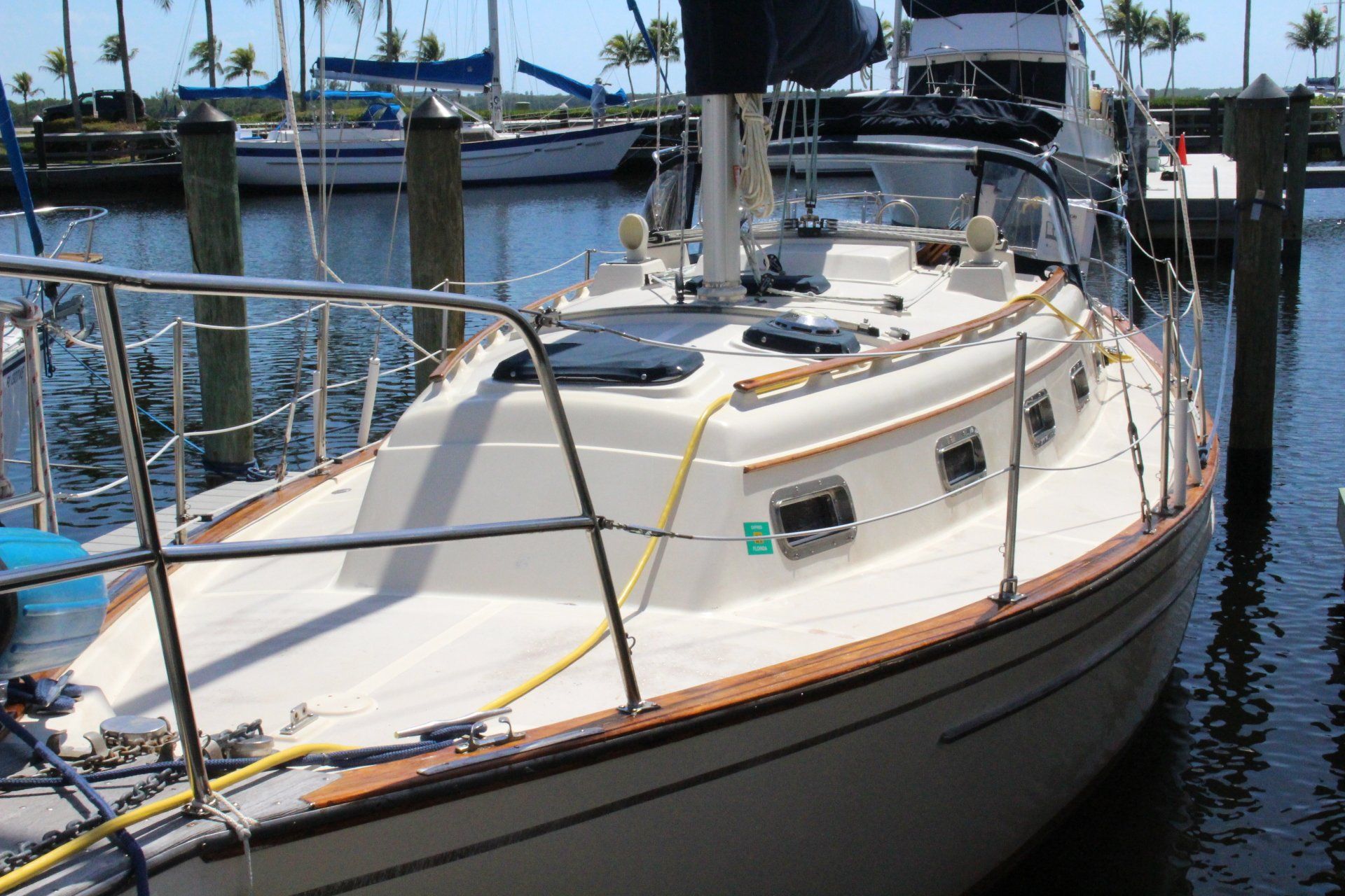 A sailboat is docked at a marina with a yellow hose attached to it