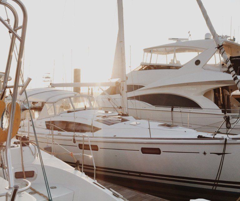 A group of boats are docked in a marina at sunset.