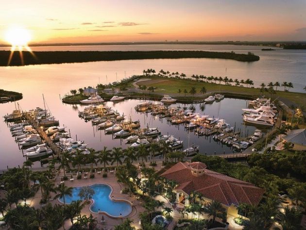 An aerial view of a marina with boats and a pool at sunset