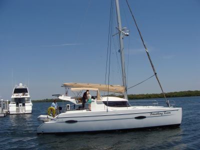 A white sailboat is floating on top of a body of water.