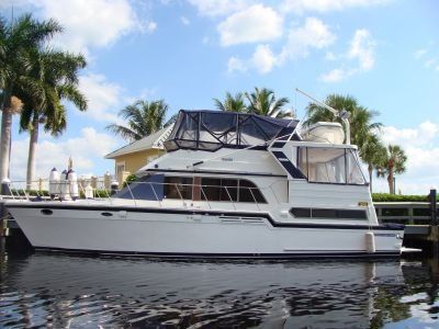 A white boat is docked at a dock with palm trees in the background