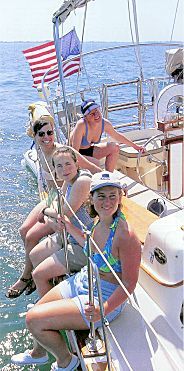 A group of people are sitting on a sailboat in the ocean.