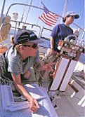 A man and a woman are sitting on a boat looking at papers.