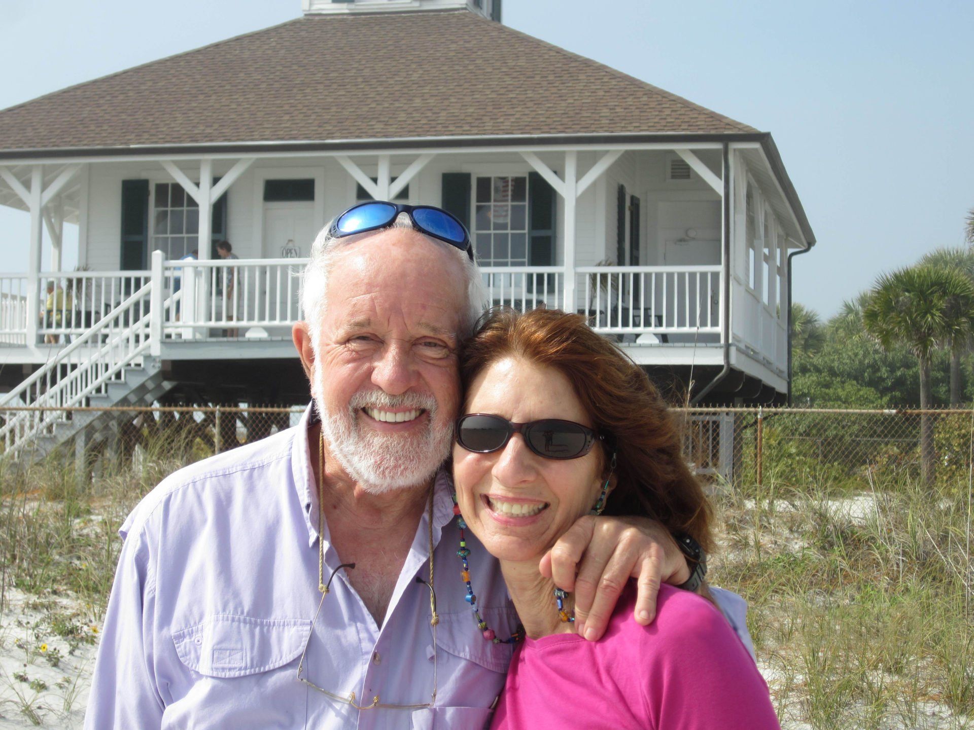 A man and woman are posing for a picture in front of a house